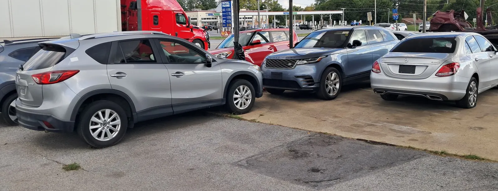 A crossover, an SUV and a sedan parked along the front of the CM Auto Sales lot.