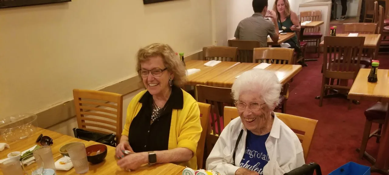 Two older women sharing a cheerful meal at a restaurant.