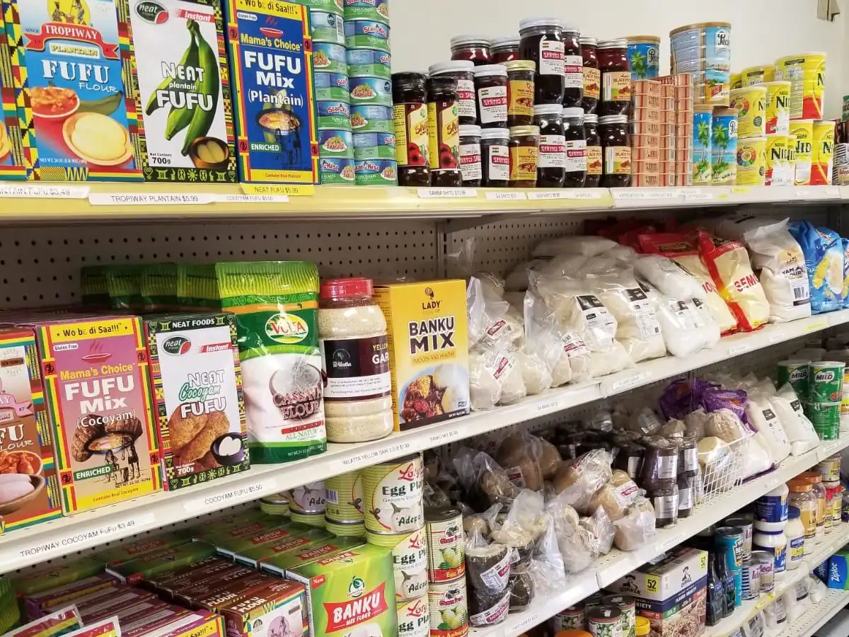Shelf stocked with fufu and banku mixes, cassava flour, grains and meal starters at LIMS Makola International Market.