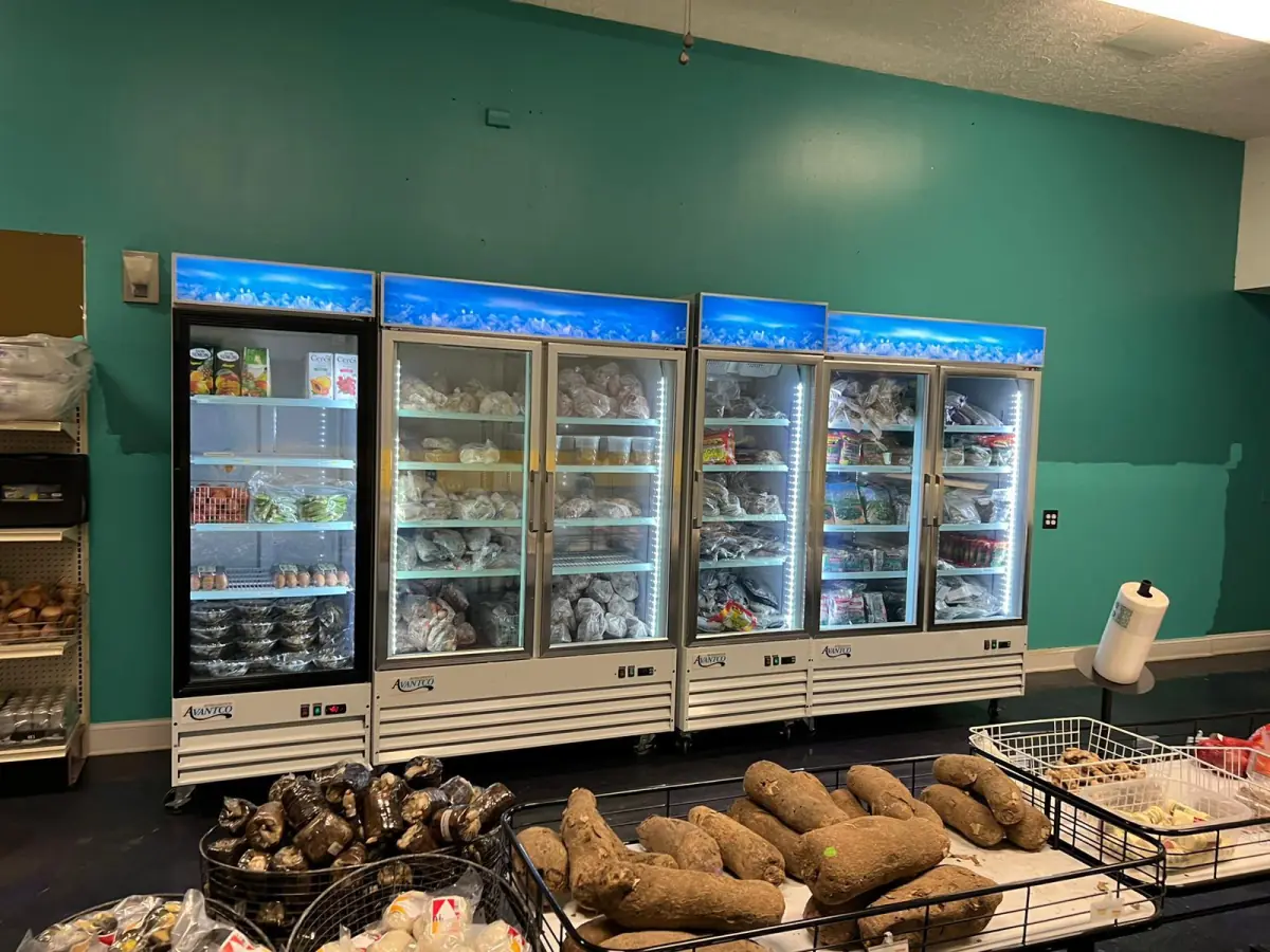 Refrigerated foods and fresh yams inside LIMS Makola International Market.