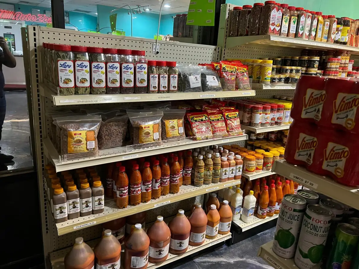 Shelf stocked with spices, sauces, palm oil and cooking ingredients at LIMS Makola International Market.